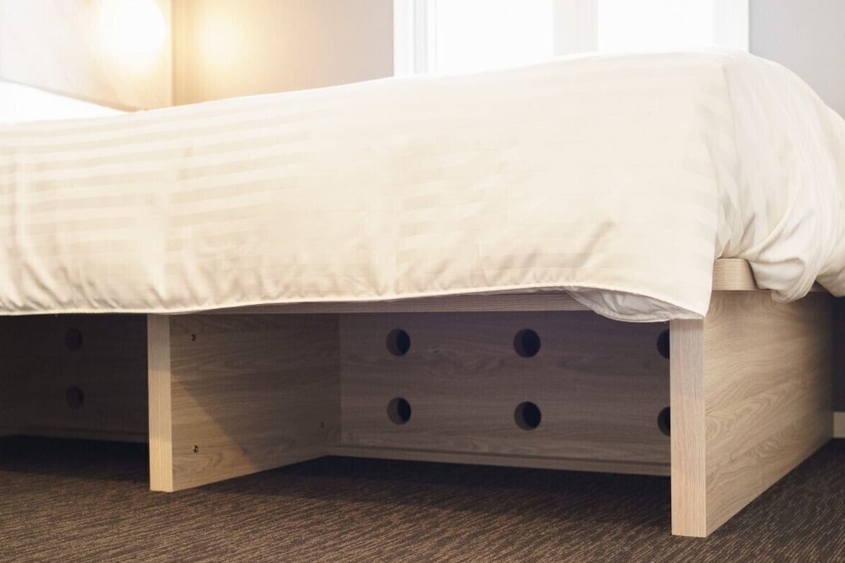 Un lit avec un cadre en bois et des tiroirs de rangement situés en dessous.