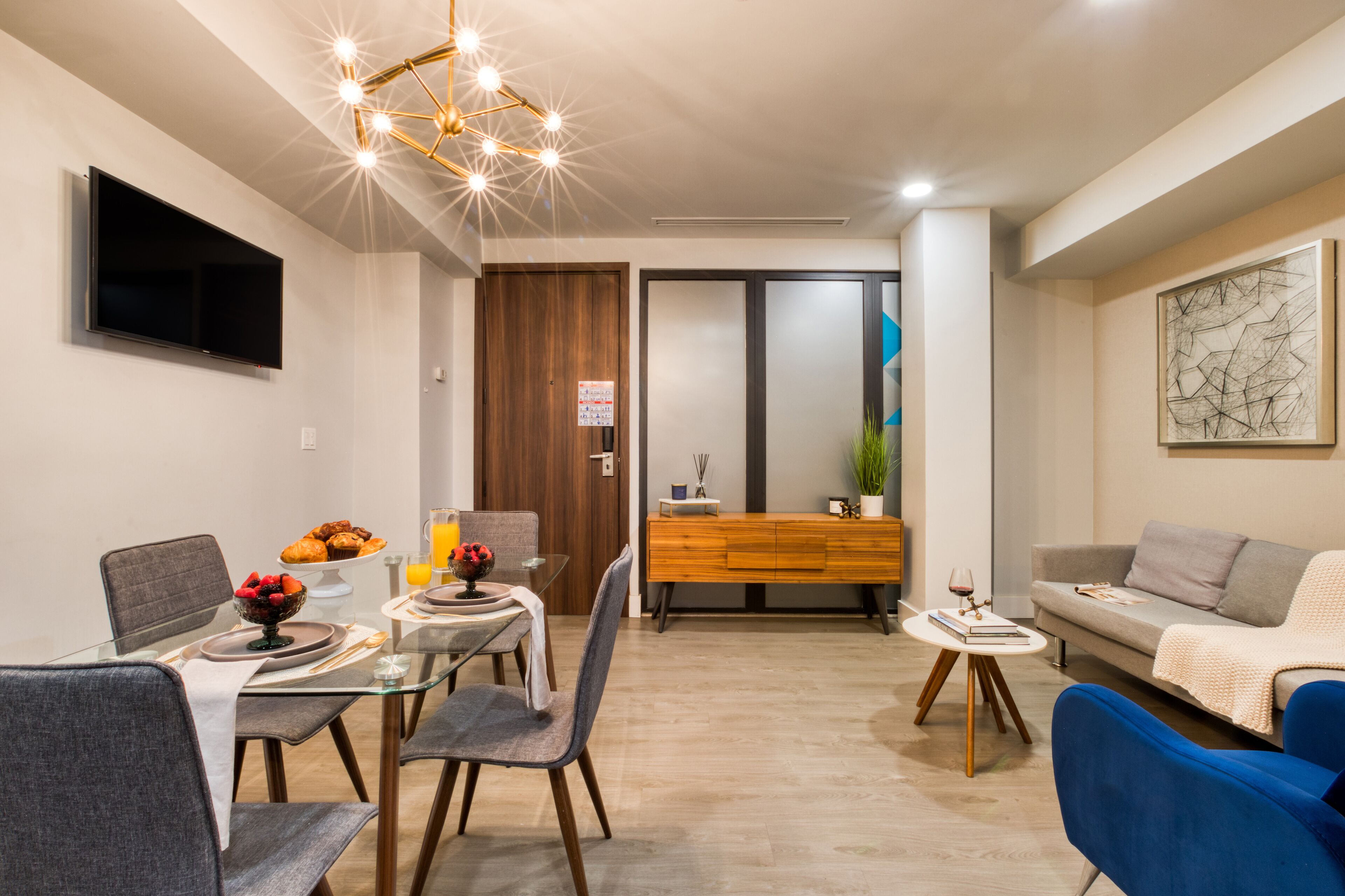 A modern living room with a dining area, a sofa, a TV, and a wooden cabinet.