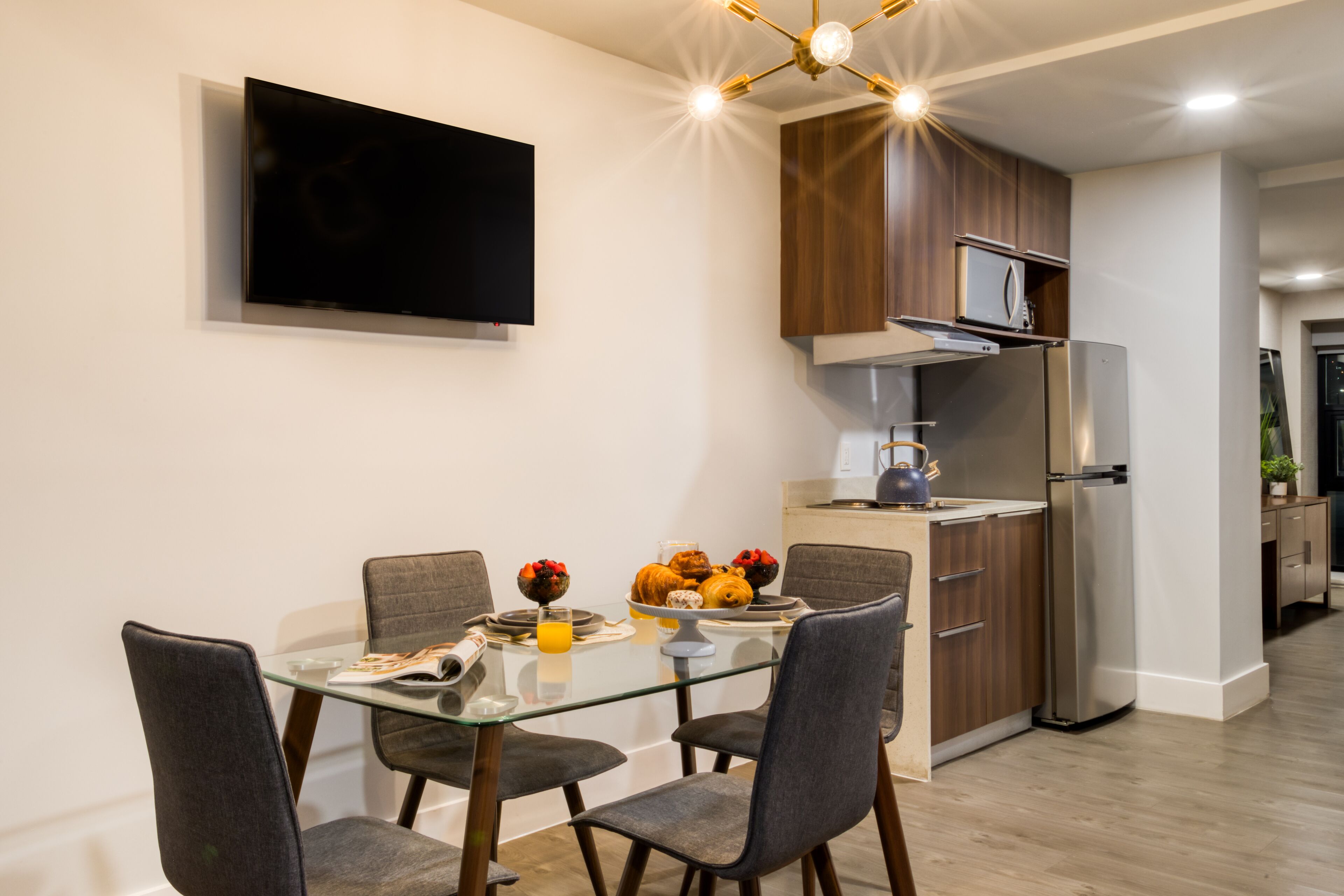 A modern kitchen with a built-in microwave, stainless steel refrigerator, and wooden cabinets.