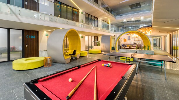 A modern indoor recreational area with a pool table, billiards, and seating areas.