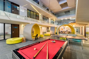 Un área recreativa interior moderna con mesa de billar, futbolín y zonas de estar.