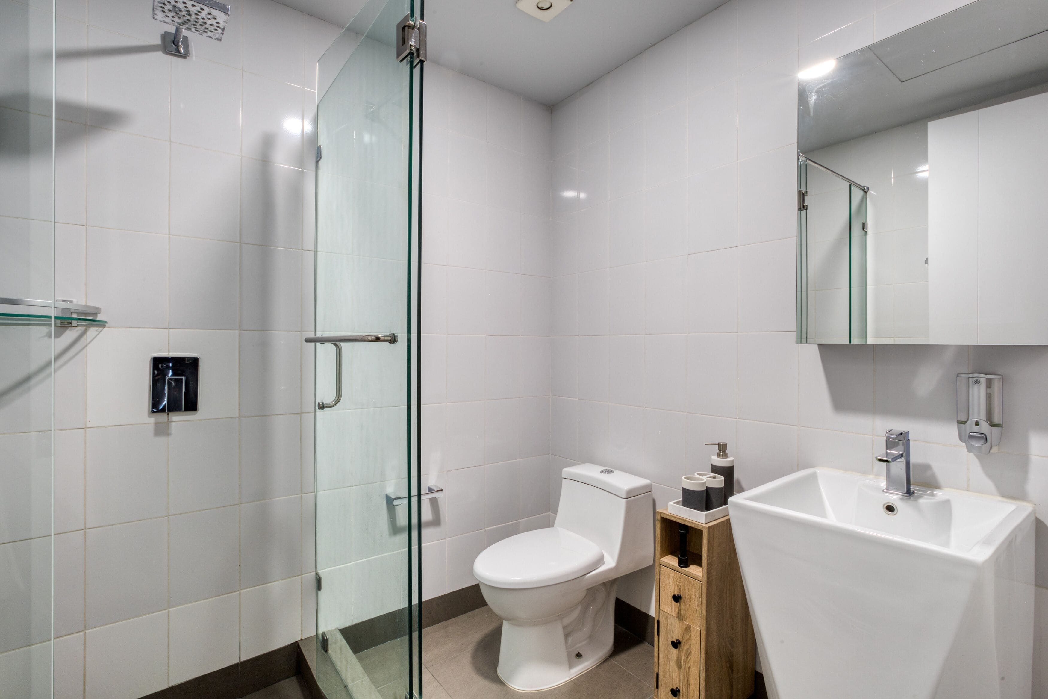 A modern bathroom with a glass shower enclosure, a white toilet, and a large sink.