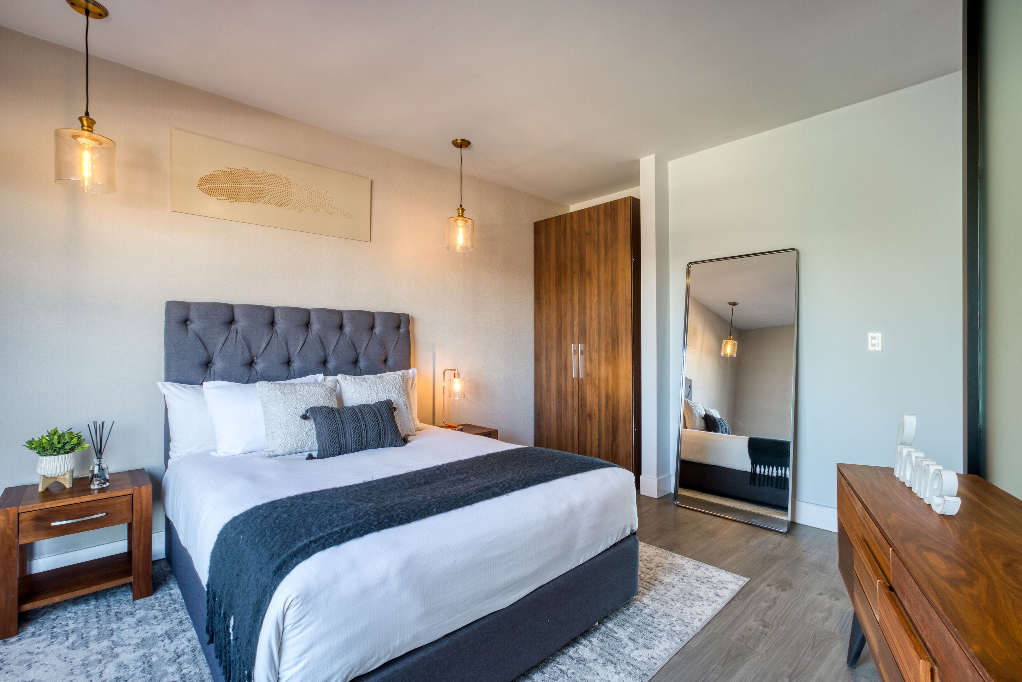 Un dormitorio moderno con una cama grande, un armario de madera y un espejo.