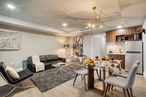 A modern living room with a black leather sofa, a glass coffee table, and a dining area with a glass table and chairs. - Eazy Rio by ULIV (Tijuana)
