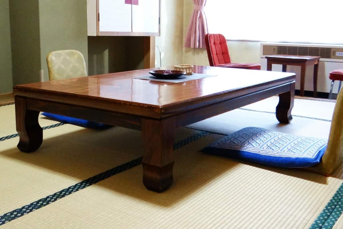 Une pièce traditionnelle avec un sol recouvert de tatamis, une table en bois, des chaises et une petite table sur laquelle se trouve un bol.