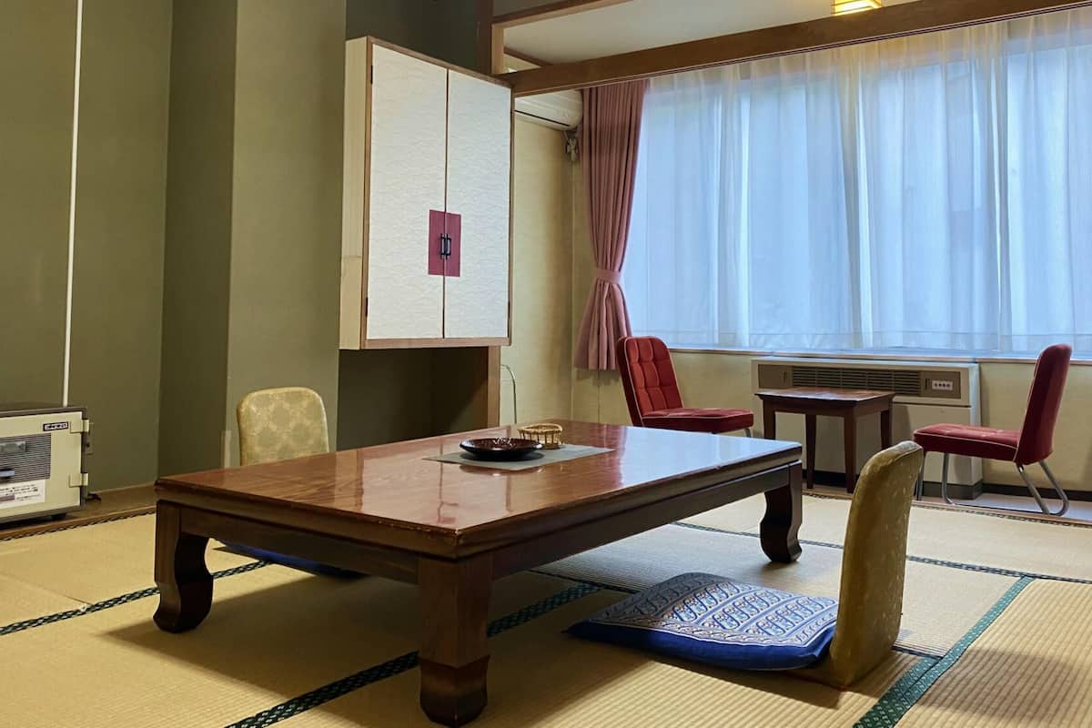 Une pièce avec une table en bois, des chaises, un buffet et une fenêtre avec des rideaux.