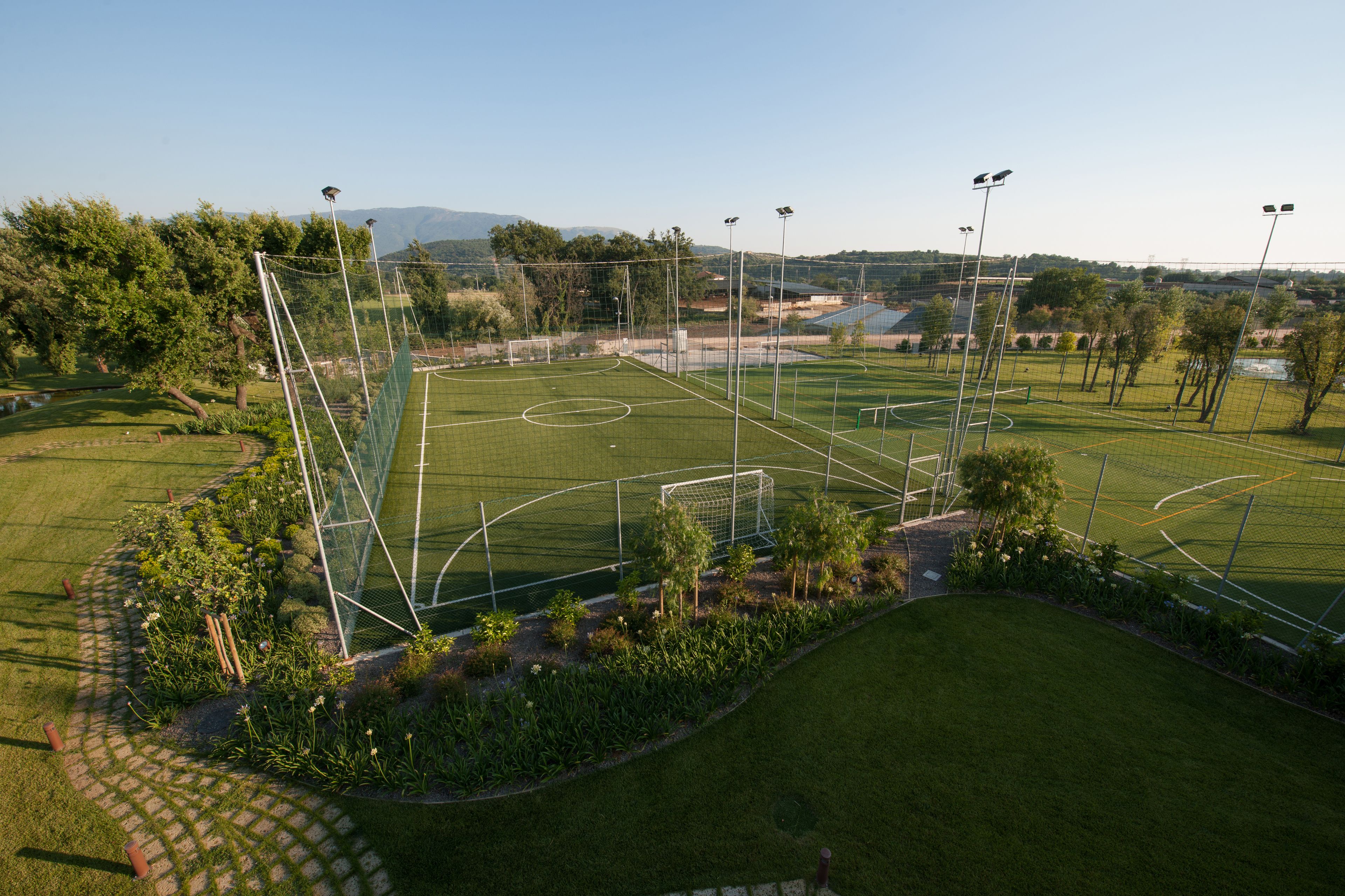 Ein Fußballfeld mit Toren, umgeben von einem Zaun und Bäumen.
