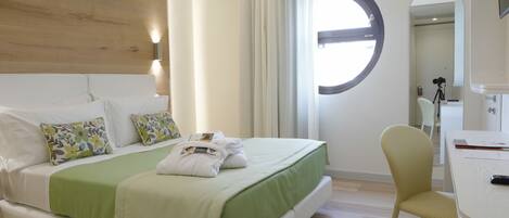 Una camera d'albergo con un letto, una sedia, una scrivania e una finestra circolare.