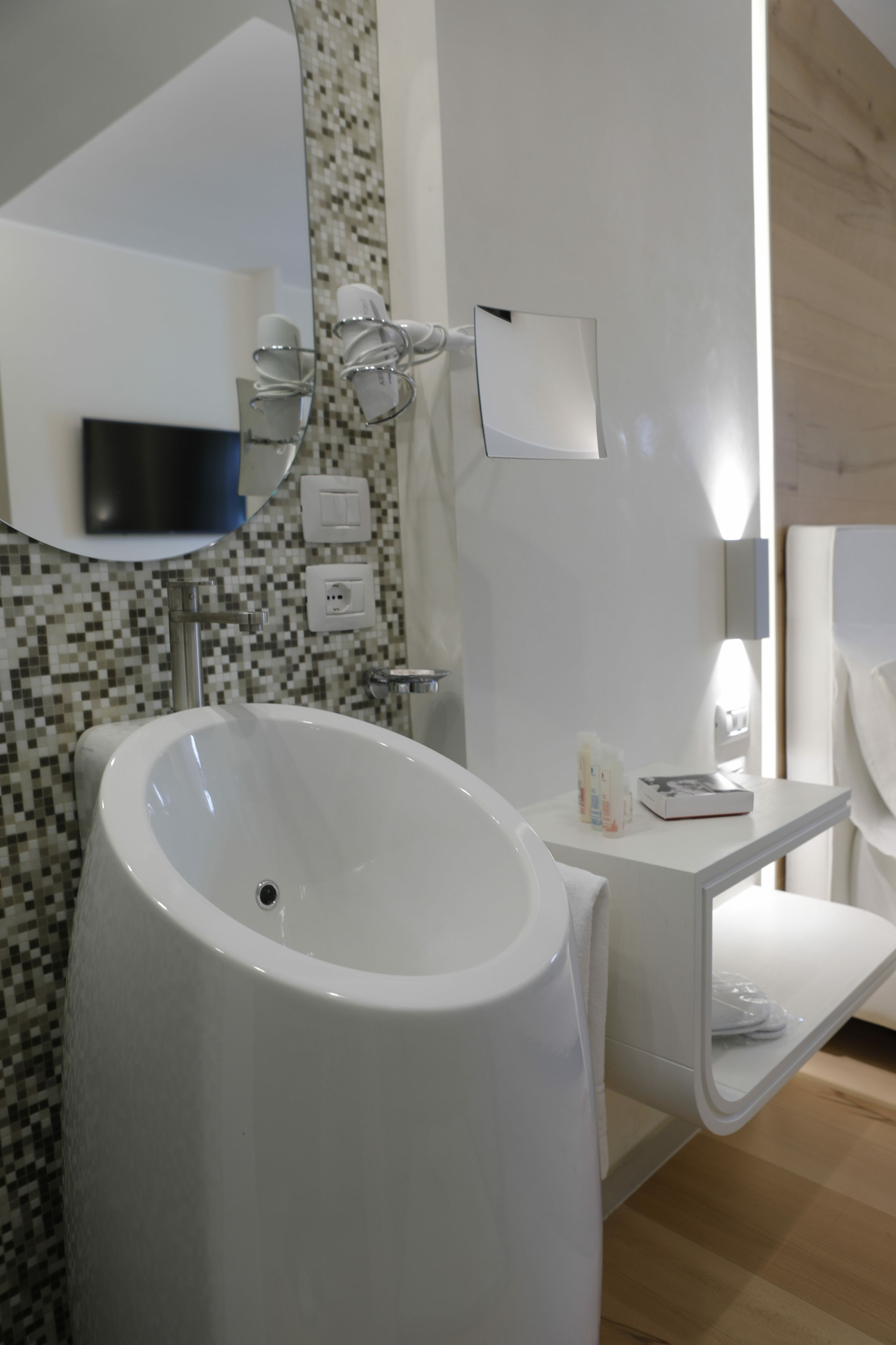 Une salle de bain moderne avec un grand lavabo blanc, un miroir et un mur recouvert de carreaux.