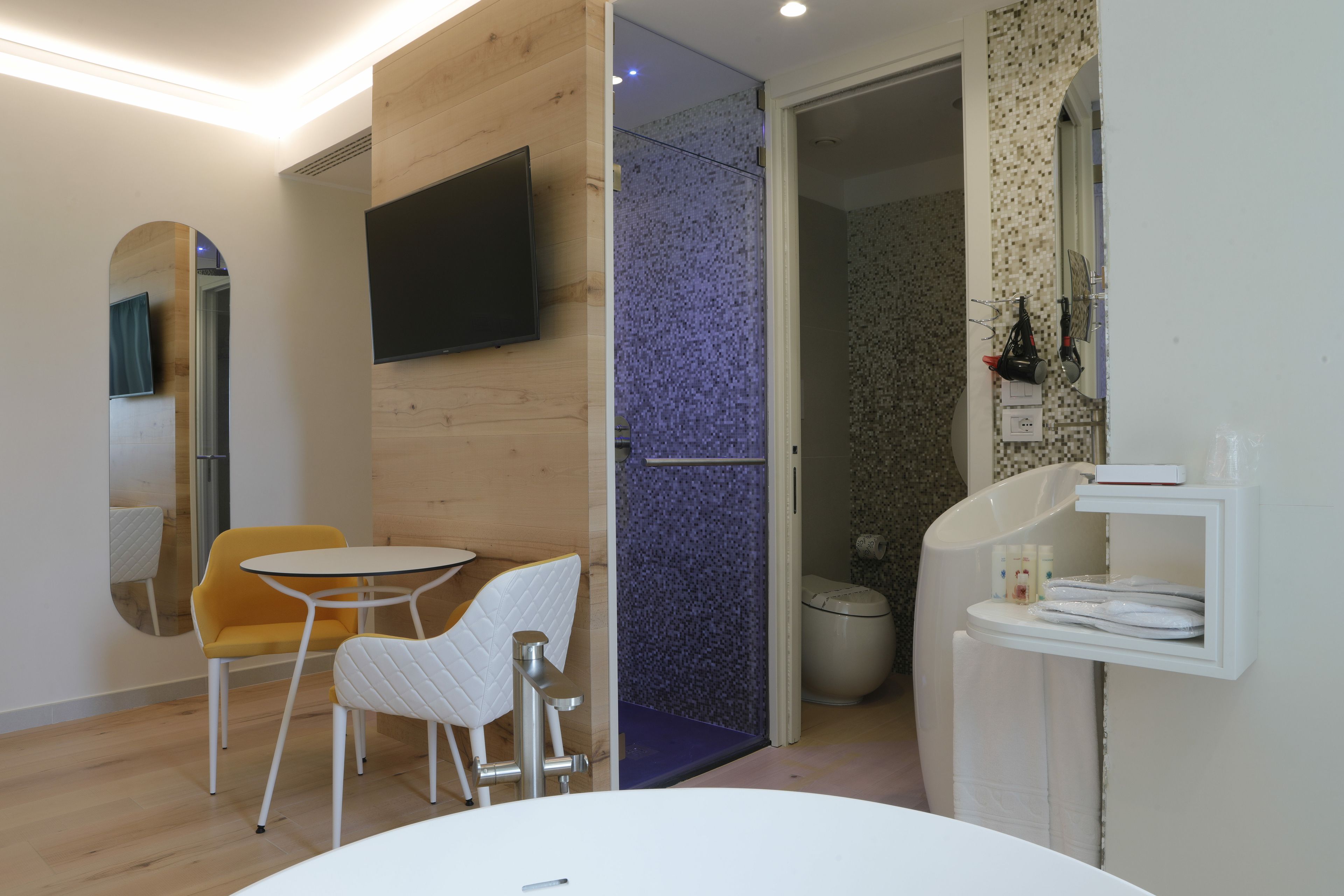 Ein modernes Badezimmer mit Dusche, Toilette und Waschbecken. Im Raum befinden sich ein kleiner Tisch und zwei Stühle.