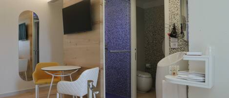 A modern bathroom with a shower, toilet, and sink. There is a small table and two chairs in the room.