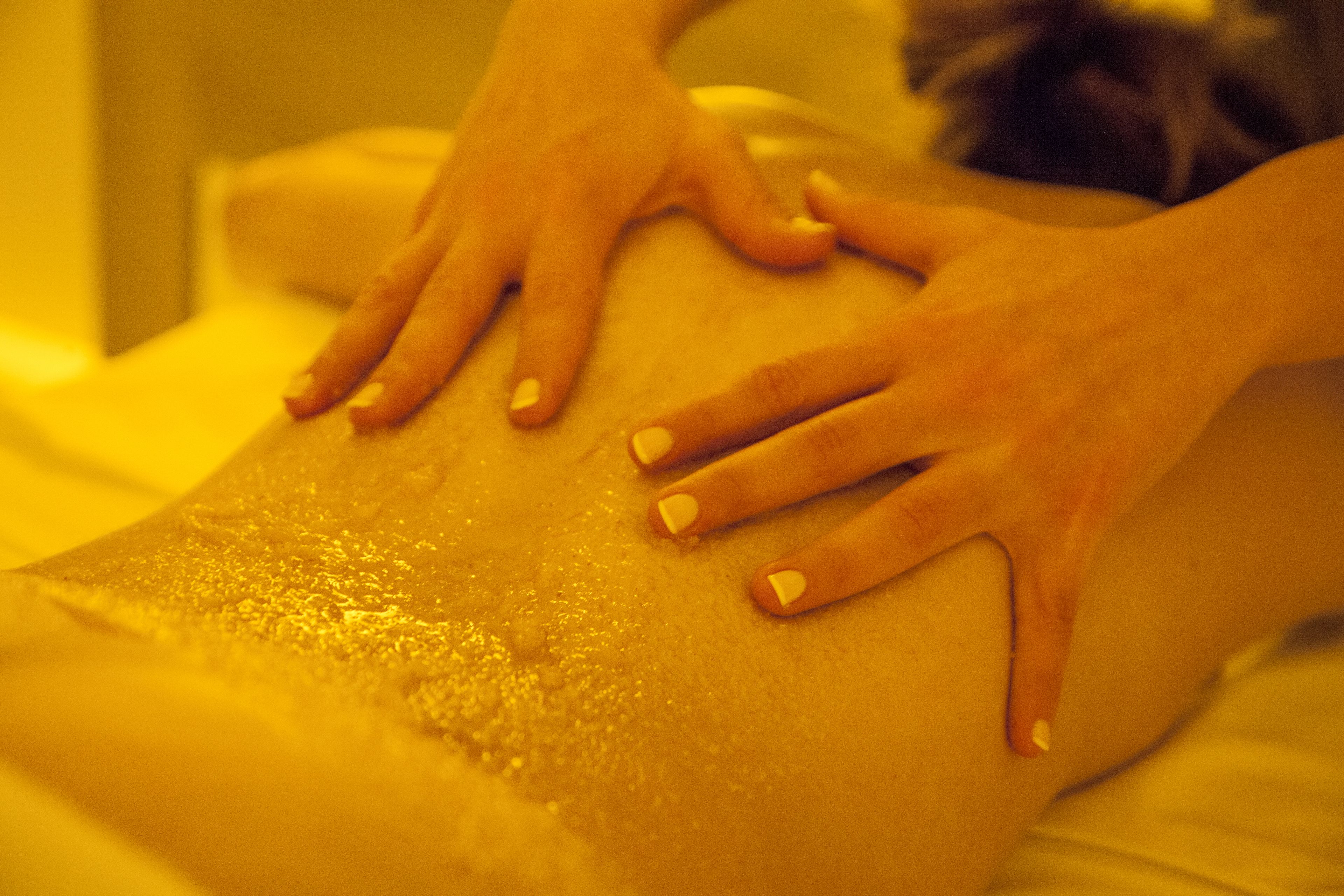 A close-up of hands performing a massage on a person's back.