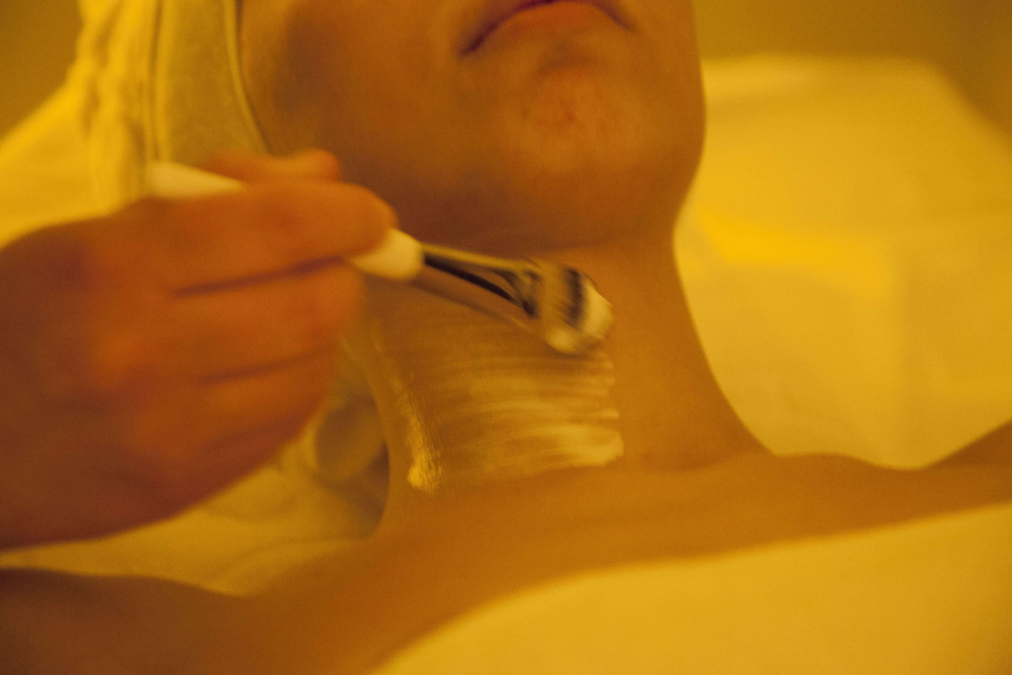 A person applying a substance to their skin.