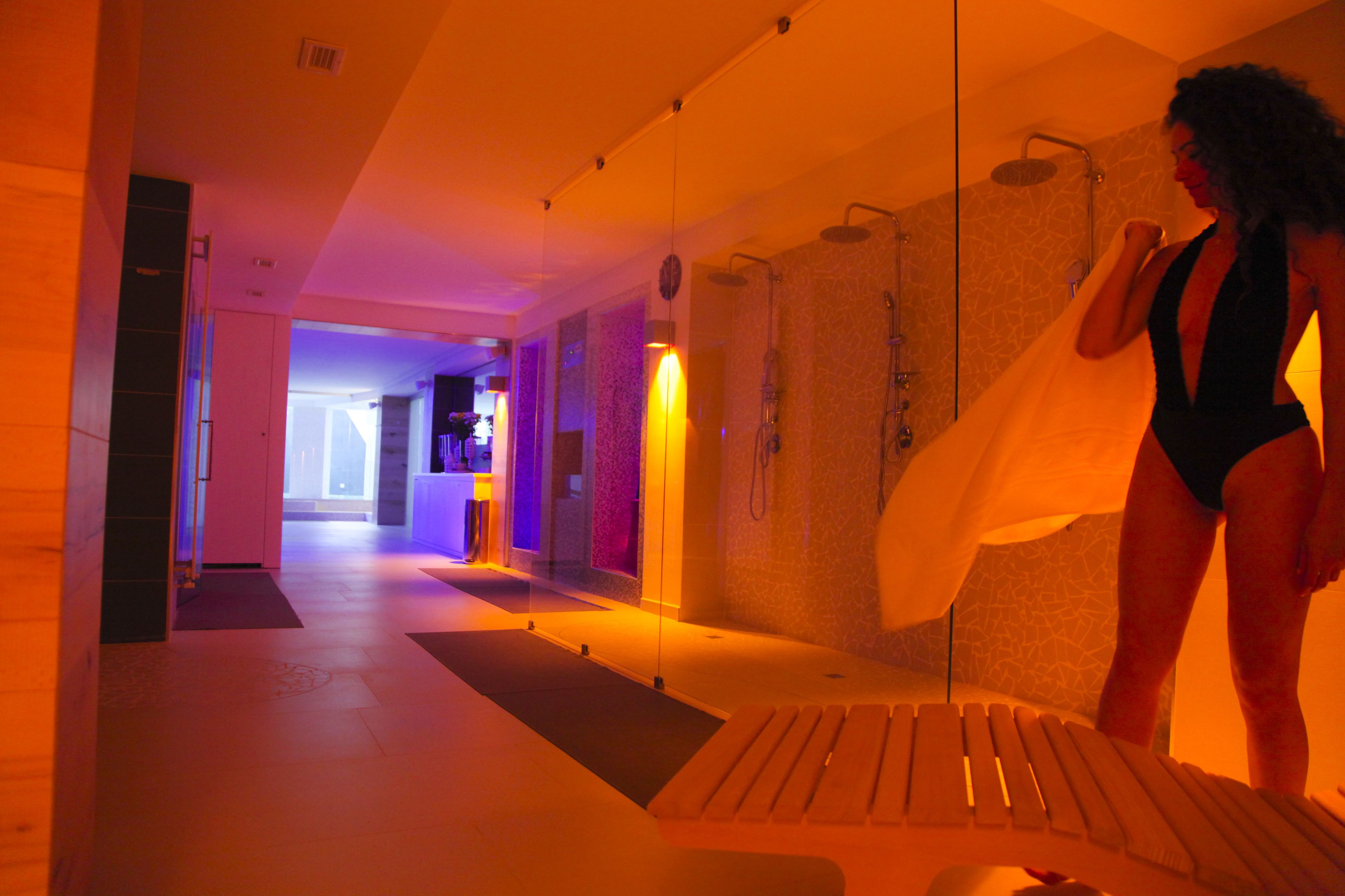 A spa area with a shower, a massage chair, and a person in a swimsuit.