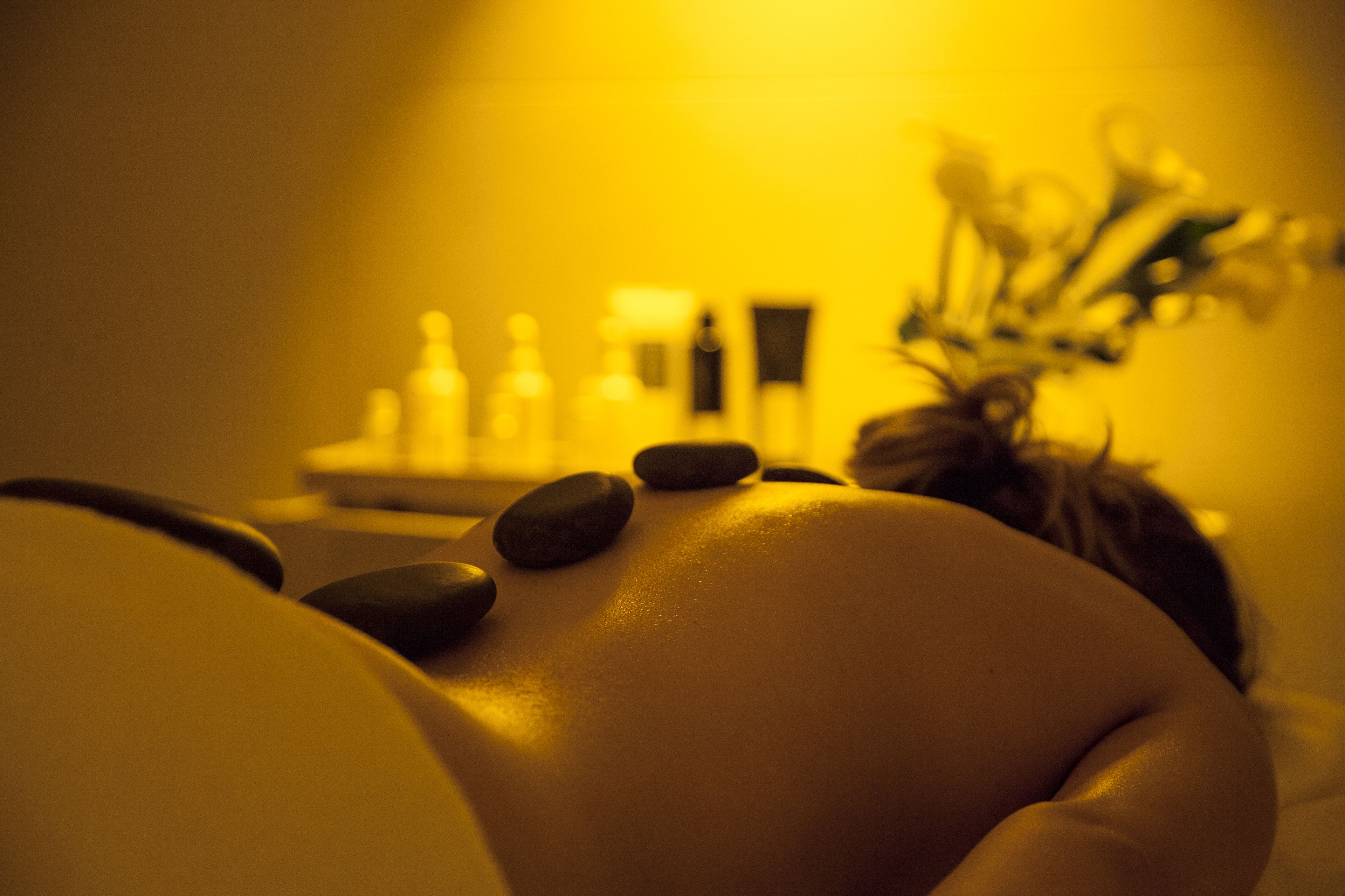 Gros plan d’une table de massage avec des pierres et une plante en pot.