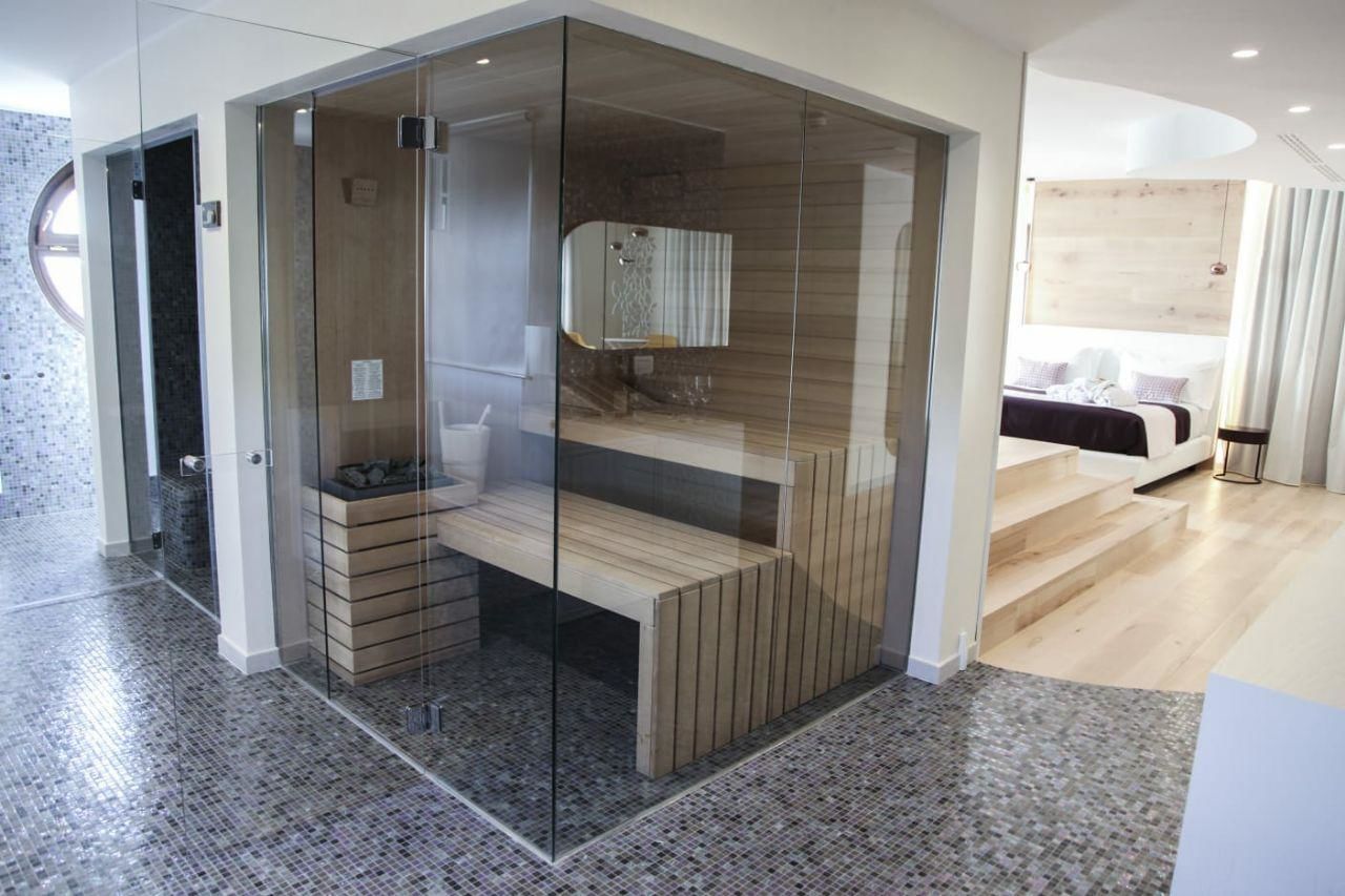 Une salle de bain moderne dotée d’une paroi de douche en verre, d’un banc en bois et d’un espace douche clairement délimité.
