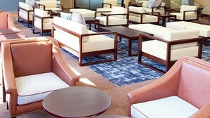 A hotel lobby with multiple seating areas, including sofas and armchairs, arranged around a central coffee table.