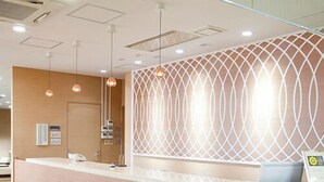 A reception desk with a curved design, a patterned wall behind it, and pendant lighting.
