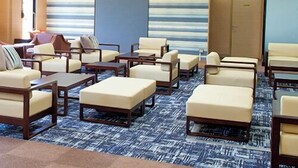 A hotel lobby with a seating area featuring sofas and armchairs, a patterned carpet, and a blue accent wall.