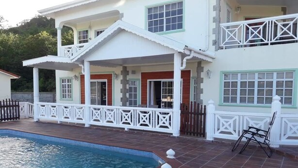 A two-story house with a swimming pool, a covered patio, and a white fence. - Rodney Heights Grande Splendour (Gros Islet)