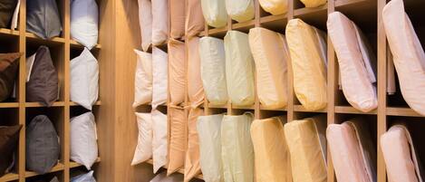 A storage area with neatly organized shelves containing various folded linens and pillows in different colors.