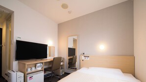 A hotel room with a bed, a desk with a flat-screen TV, a chair, a small kitchenette, and a mirror. - Super Hotel Kitami (Kitami)