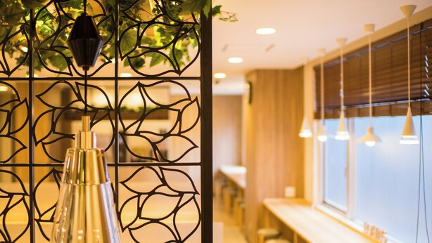 A modern interior with a decorative metal partition, pendant lighting, and a bar area with stools. - Super Hotel Kitami (Kitami)