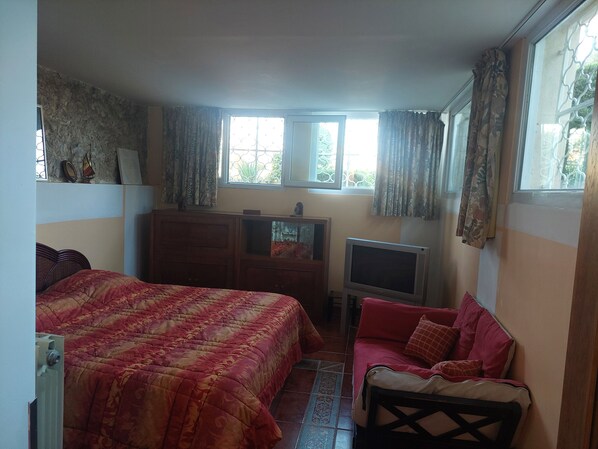 Un dormitorio con cama, televisor, escritorio y silla.