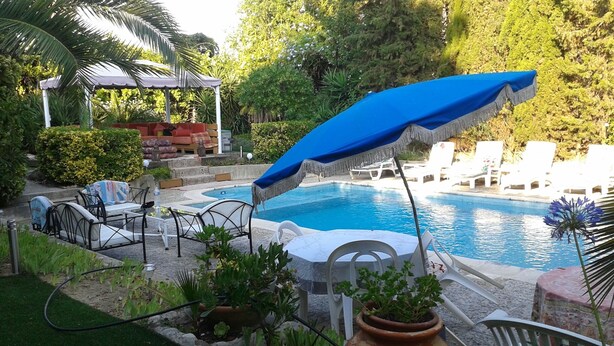 Ein Schwimmbecken mit Liegestühlen und einer überdachten Sitzgelegenheit.