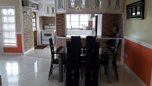 A modern kitchen with white cabinets, a central island, and a dining area with black chairs. - Balata Splendour Apartment (Gros Islet)