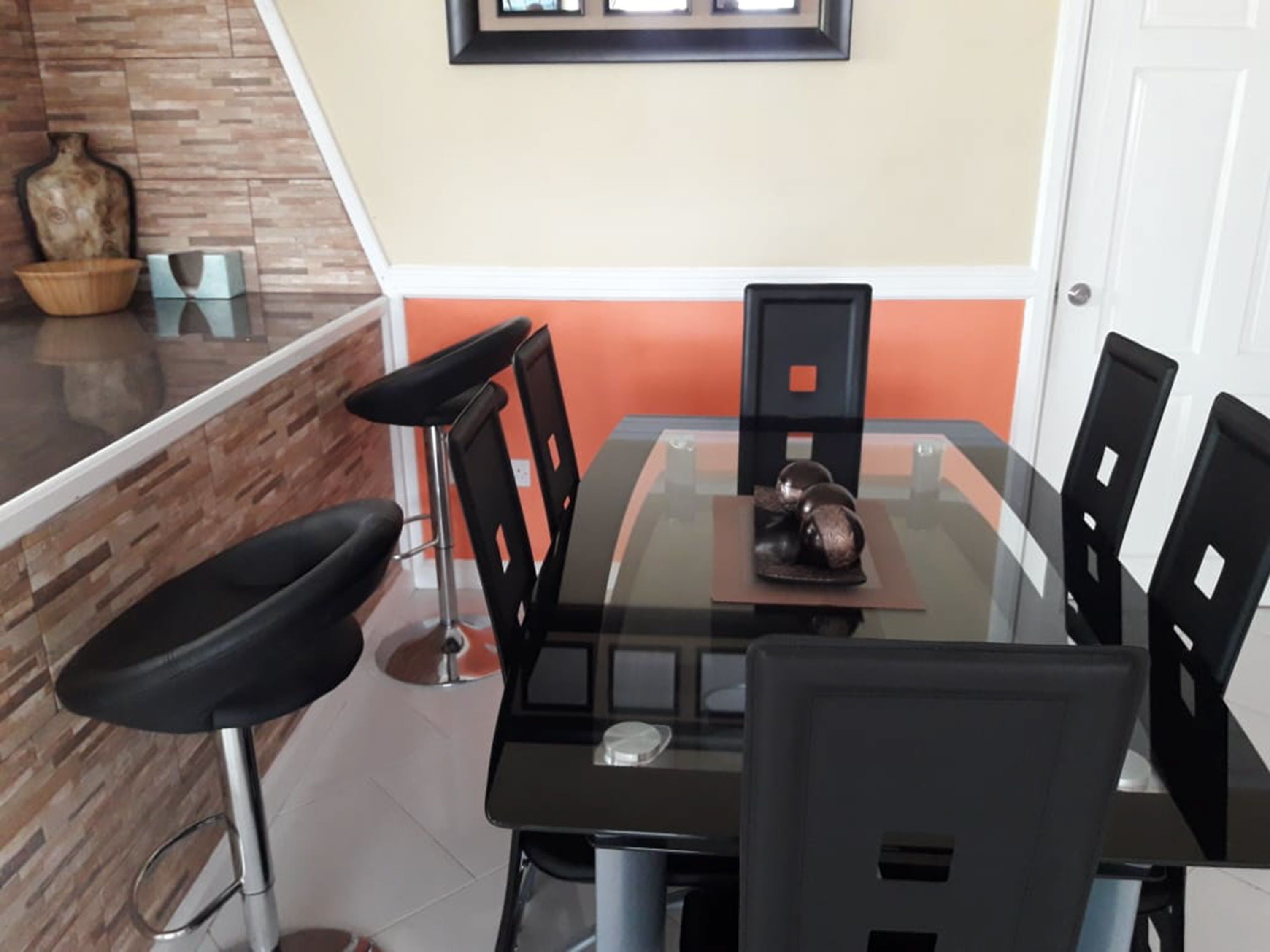 Un coin repas avec une table en verre, des chaises noires et une sculpture décorative.