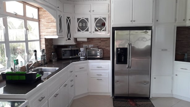A modern kitchen with white cabinetry, a stainless steel refrigerator, a microwave, and a coffee maker. - Balata Splendour Apartment (Gros Islet)