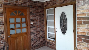 A corner of a building with a wooden door with glass panels and a white door with a decorative glass design. - Balata Splendour Apartment (Gros Islet)