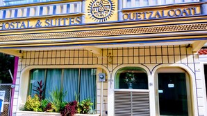 Un bâtiment portant une enseigne indiquant « Services postaux et chambres » et « Quetzalcoatl », ce qui laisse supposer qu’il s’agit d’un hôtel ou d’un établissement proposant des hébergements.