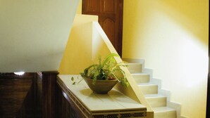 Un escalier avec une rampe en bois et un pot de fleurs placé sur le palier.
