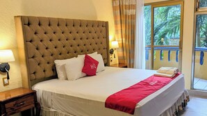 Une chambre d’hôtel avec un grand lit, une table de chevet, une lampe et une vue sur l’extérieur.