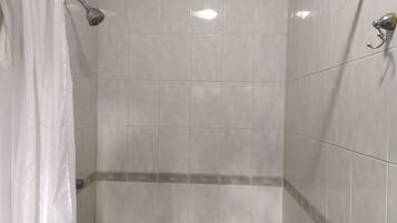 Zona de ducha con azulejos blancos y ducha.