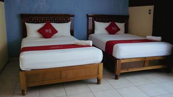 Dos camas de madera con sábanas blancas y almohadas rojas que indican "HQ".