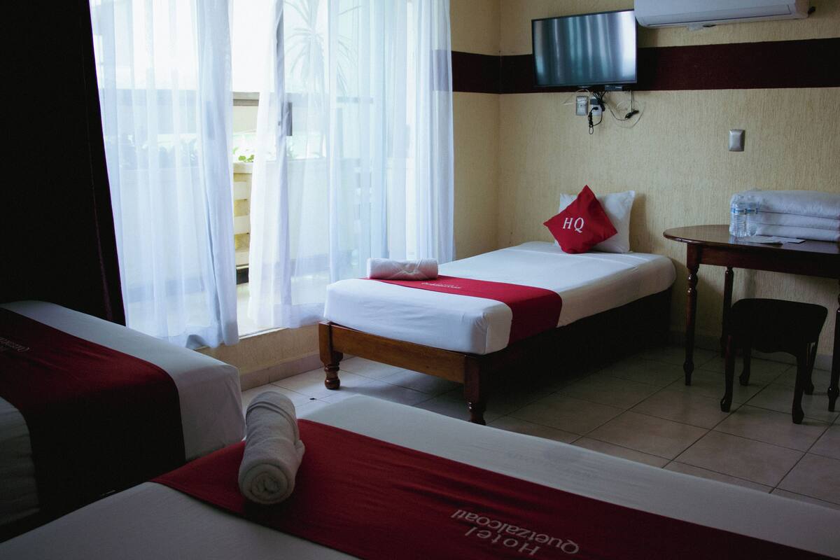 Une chambre d’hôtel avec deux lits, une télévision, un bureau et une chaise.