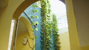 Une salle de bain avec un mur jaune, une porte bleue et un miroir qui reflète un lavabo et un porte-serviettes.