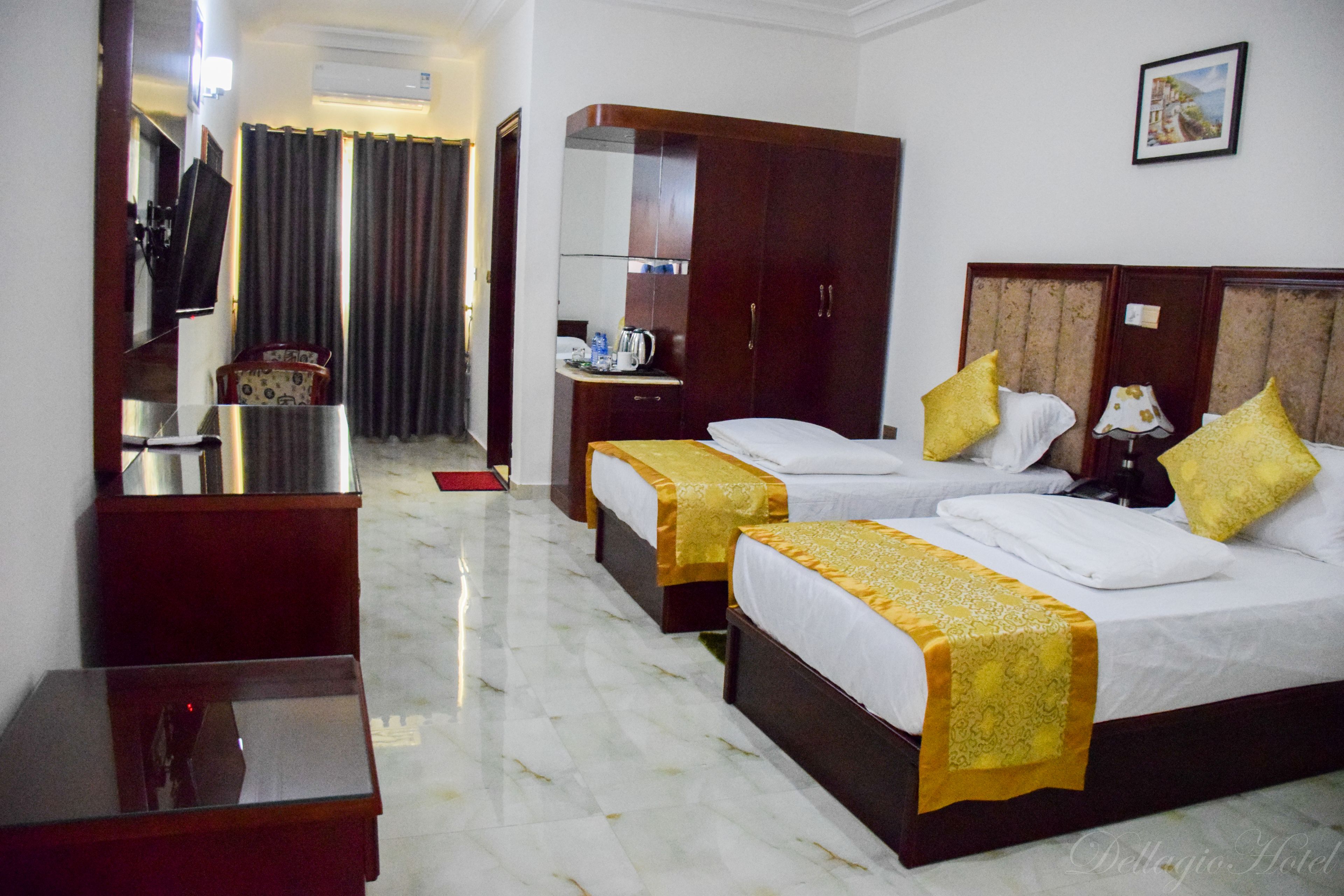 A hotel room with two beds, a desk, a chair, a wardrobe, and a mirror.