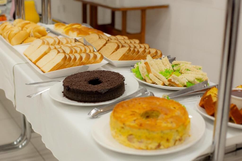 A buffet with various food items including cakes, sandwiches, and a quiche.