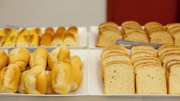 Un bufé con diversos tipos de pan, incluyendo panecillos y pan de molde.