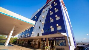 A hotel with a blue and white facade, a reception area, and a visible sign for 'SEJA BEM VINDO'.