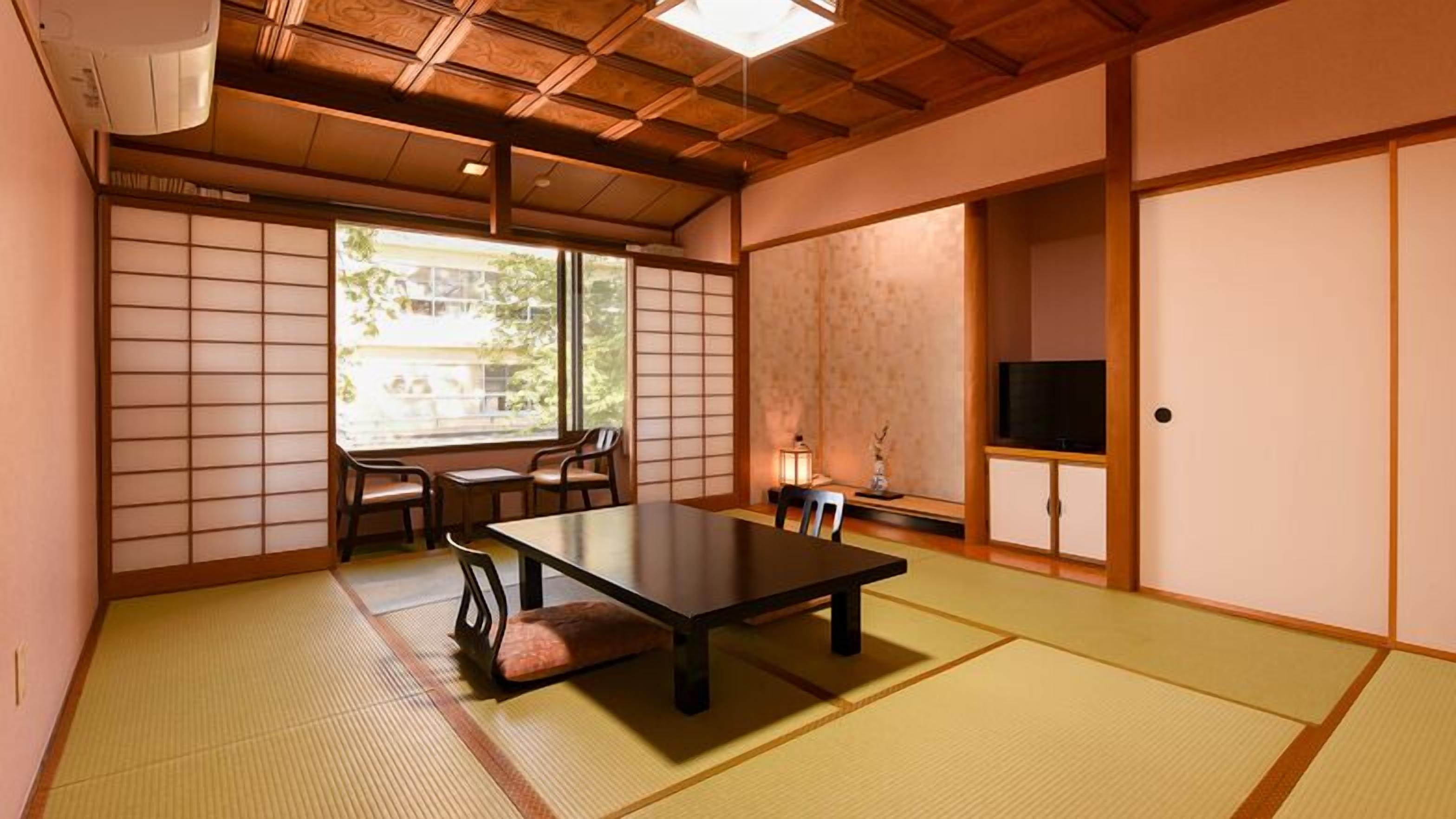 Una habitació japonesa tradicional amb terra de tatami, una taula baixa, cadires, televisió i portes corredisses.