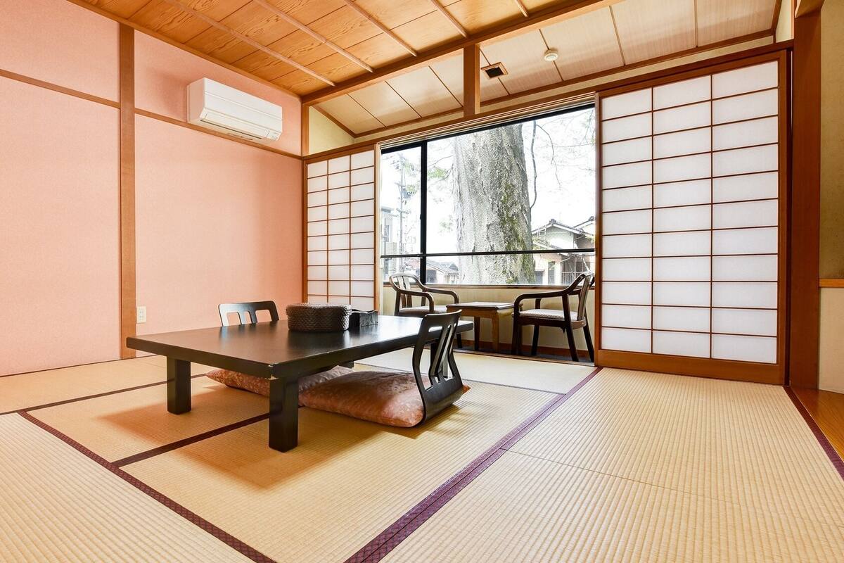 Ein traditioneller japanischer Raum mit Tatami-Boden, einem niedrigen Tisch und Schiebetüren.