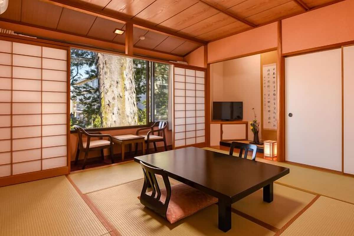 Ein traditioneller japanischer Raum mit Tatami-Böden, einem niedrigen Tisch und verschiebbaren Türen.