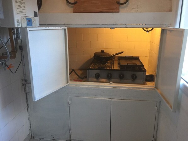 A compact kitchen with a gas stove, a small sink, and a white cabinet.