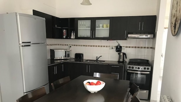 A modern kitchen with dark cabinetry, a stainless steel refrigerator, a gas stove, and a white bowl on the table.
