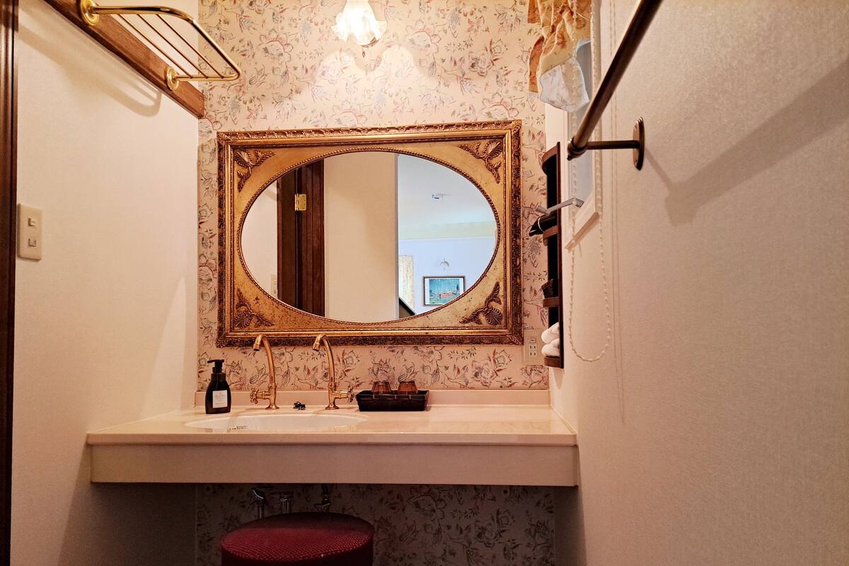 A bathroom with a large mirror, a sink, and a red toilet.